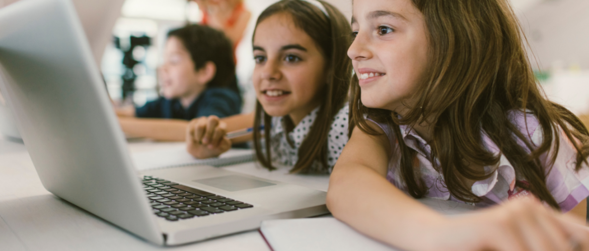 Two elementary school-aged girls looking at an open laptop
